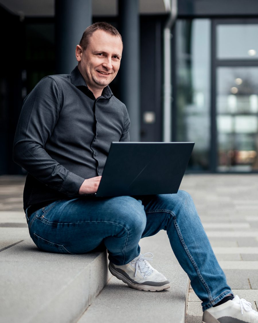 Maik Böhme, Inhaber von Smart Building Böhme Maik, mit Notebook vor einem Bürogebäude